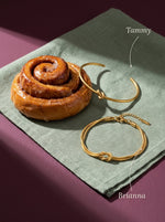 Lundholm Tammy open bangle en Brianna dubbele armband met knoop goudkleurig, met hun namen erbij, naast een kaneelknoop
