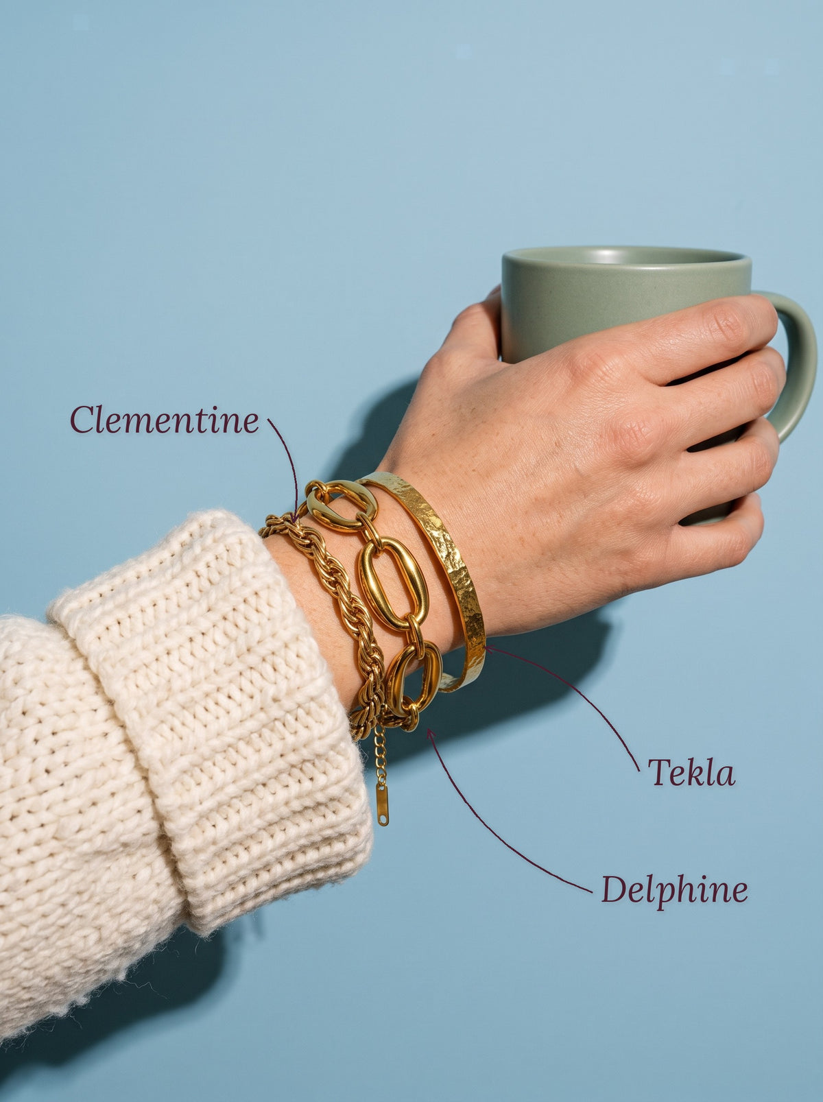 Lundholm Tekla gehamerde bangle, Clementine gedraaide schakelarmband en Delphine grove schakelarmband goudkleurig om de pols, met hun namen erbij