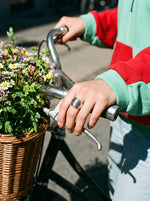 Lundholm Vanja chunky dome ring zilverkleurig gedragen, hand op een fietsstuur met bloemen