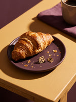 Lundholm Velia geometrische ruit oorstekers goudkleurig op een bordje naast een croissant