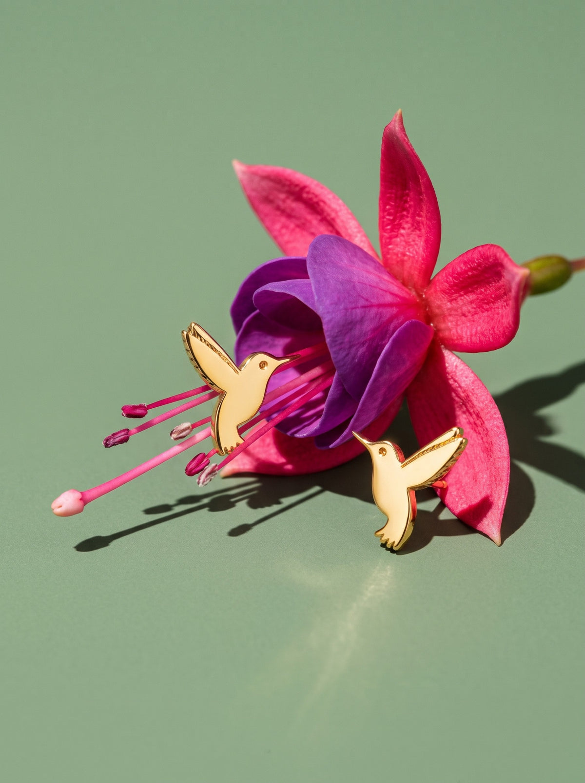 Lundholm Vivian kolibrie oorknopjes goudkleurig bij een fuchsia bloem