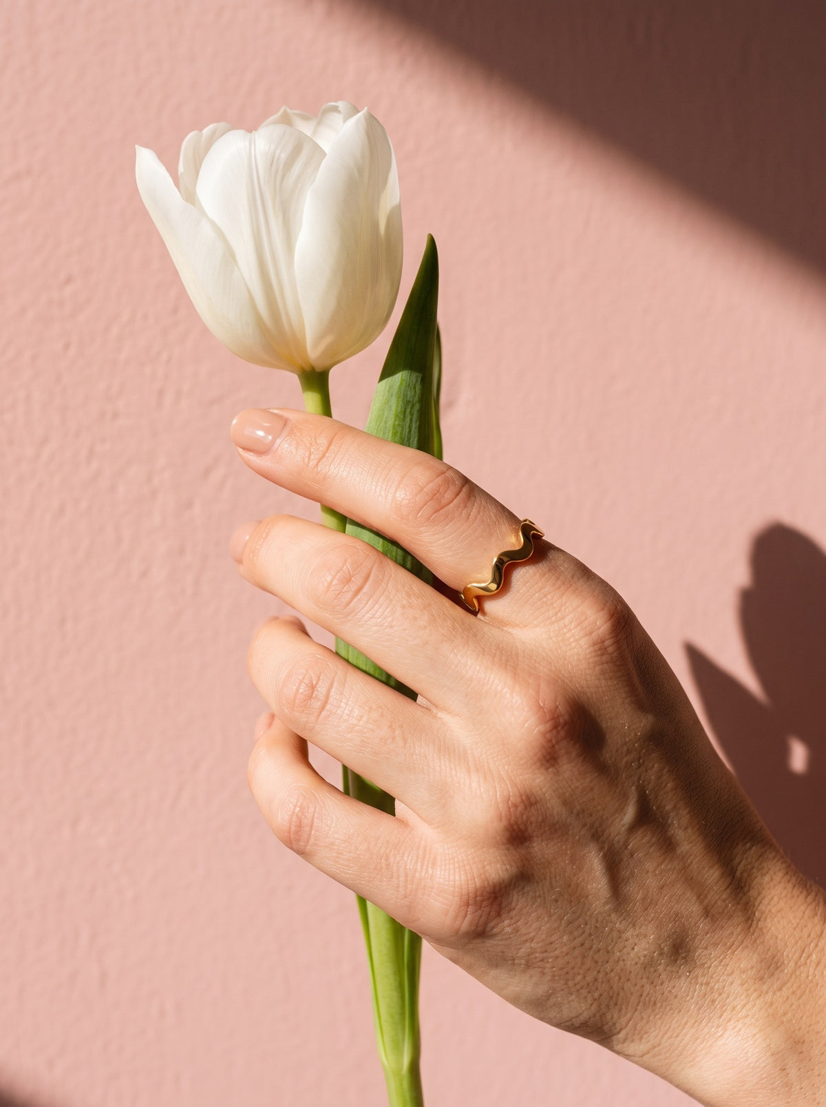 Lundholm Zia zigzag ring goudkleurig gedragen, hand met een witte tulp