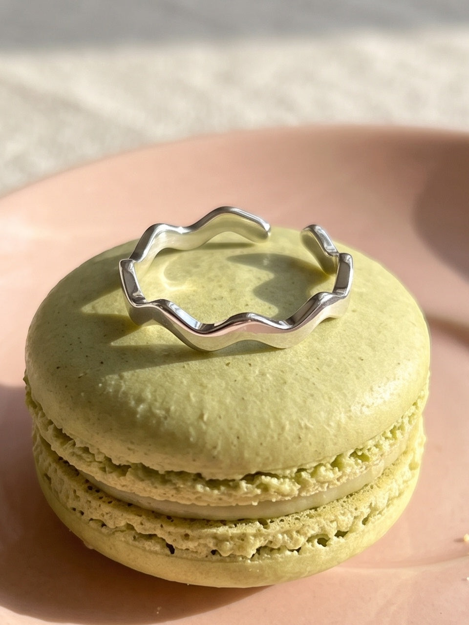 Close-up van de Lundholm Zia zigzag ring zilverkleurig op een pistache macaron