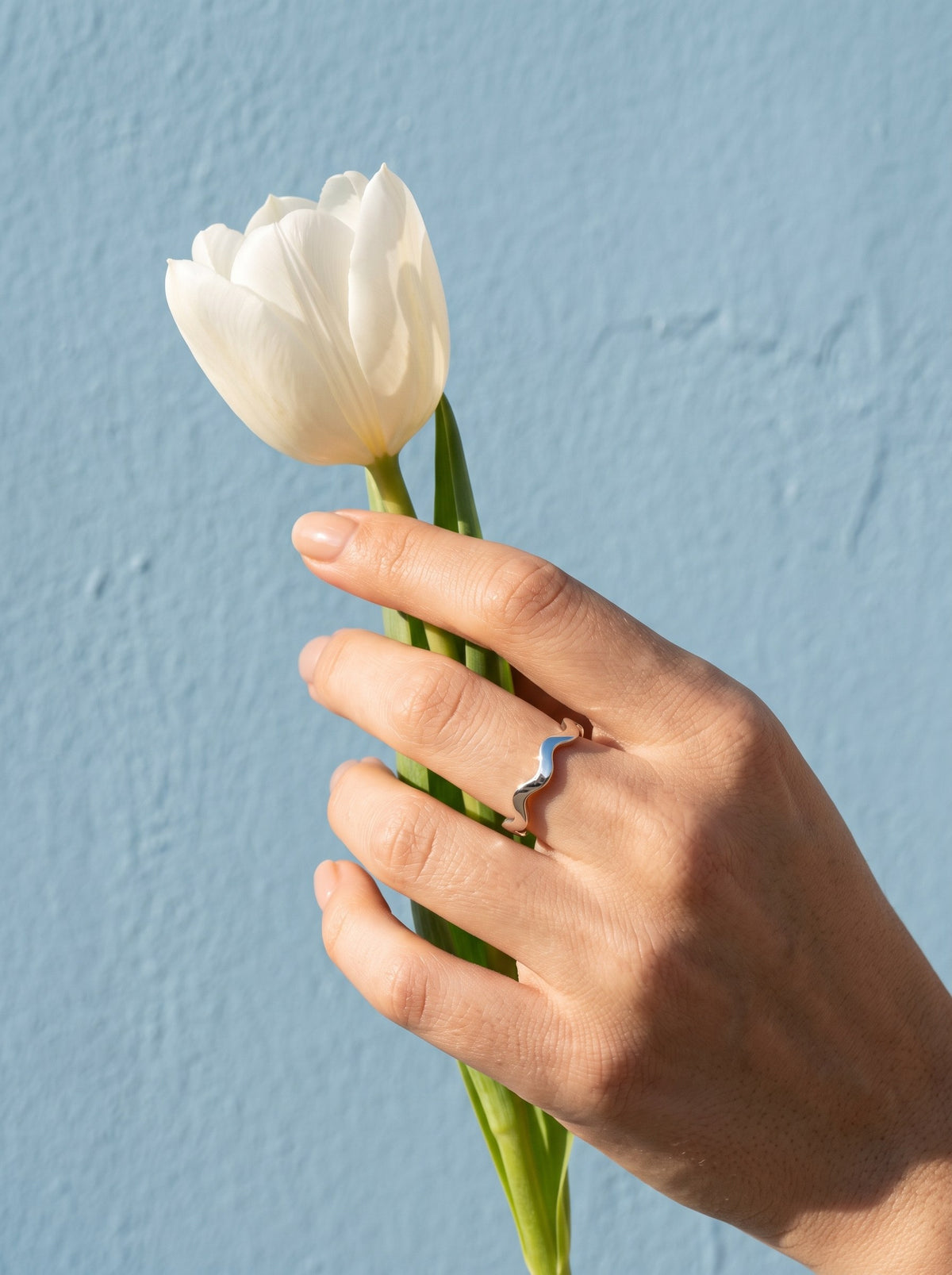 Lundholm Zia zigzag ring zilverkleurig gedragen, hand met een witte tulp